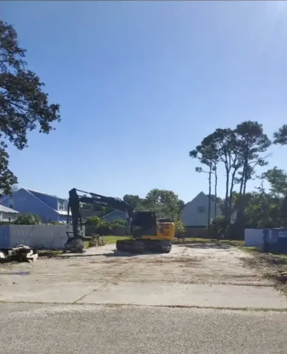 Excavator on a cleared lot between homes after a teardown