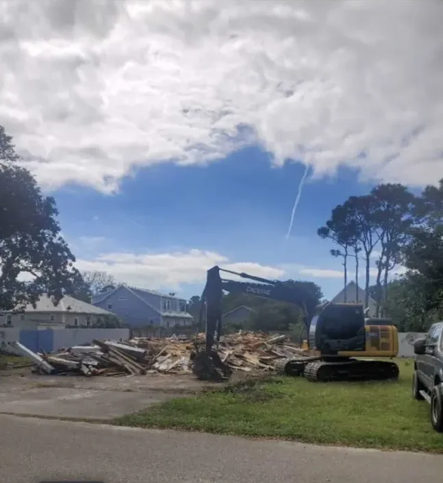 Excavator tearing down an old wood-frame house on a lot near Burgaw, NC