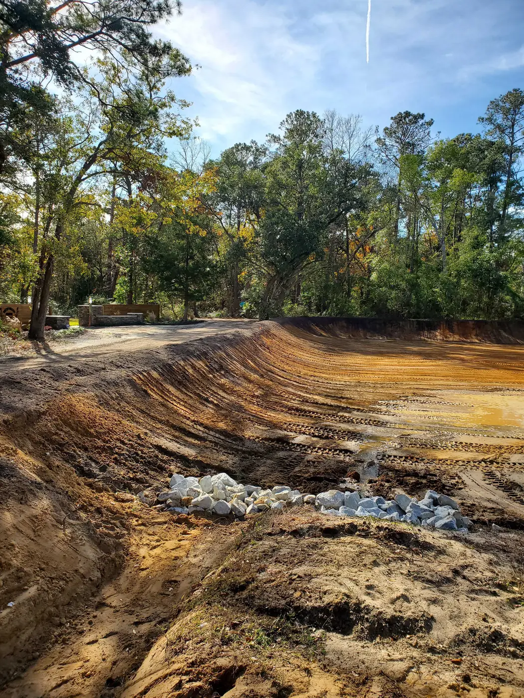 excavation cost in North Carolina, a freshly dug cut with sloped dirt banks and stone set in the bottom